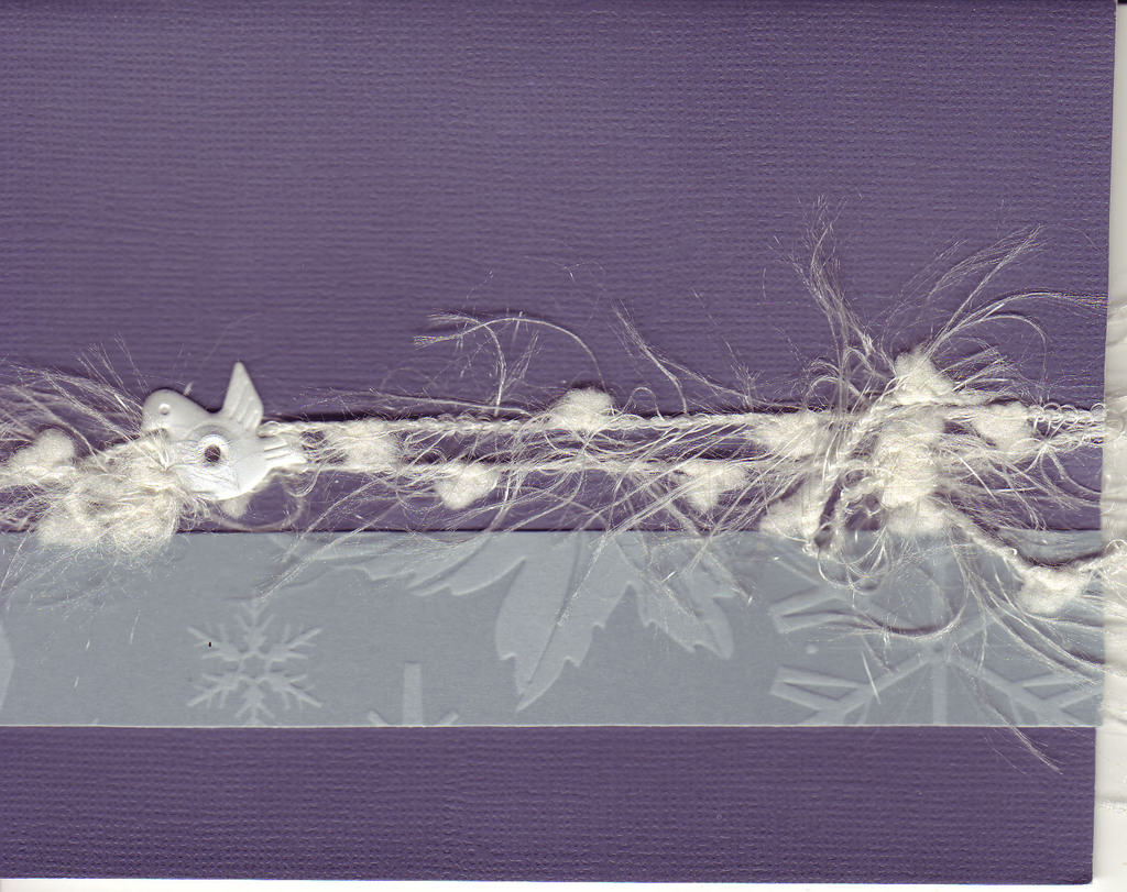 068 - A band of snowflake paper and snow-like thread held on to a deep purple card by a dove brad
