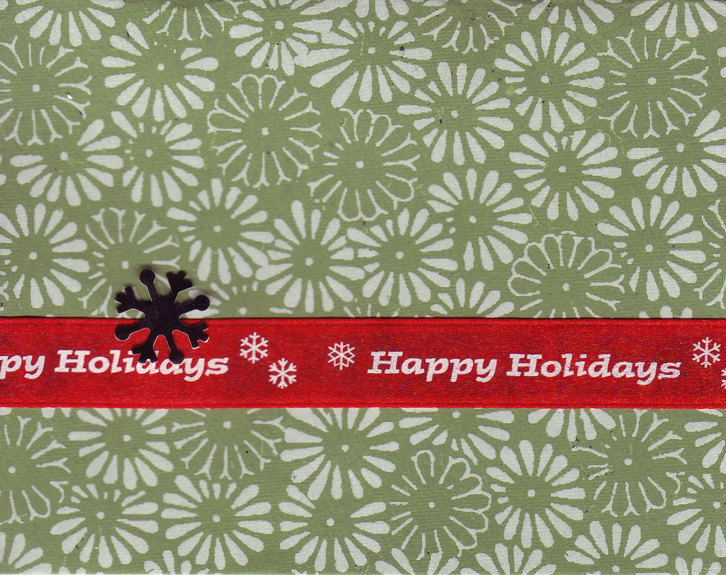 072 A red 'Happy holidays' ribbon attached to a richly textured green paper with a white floral print by a snowflake brad