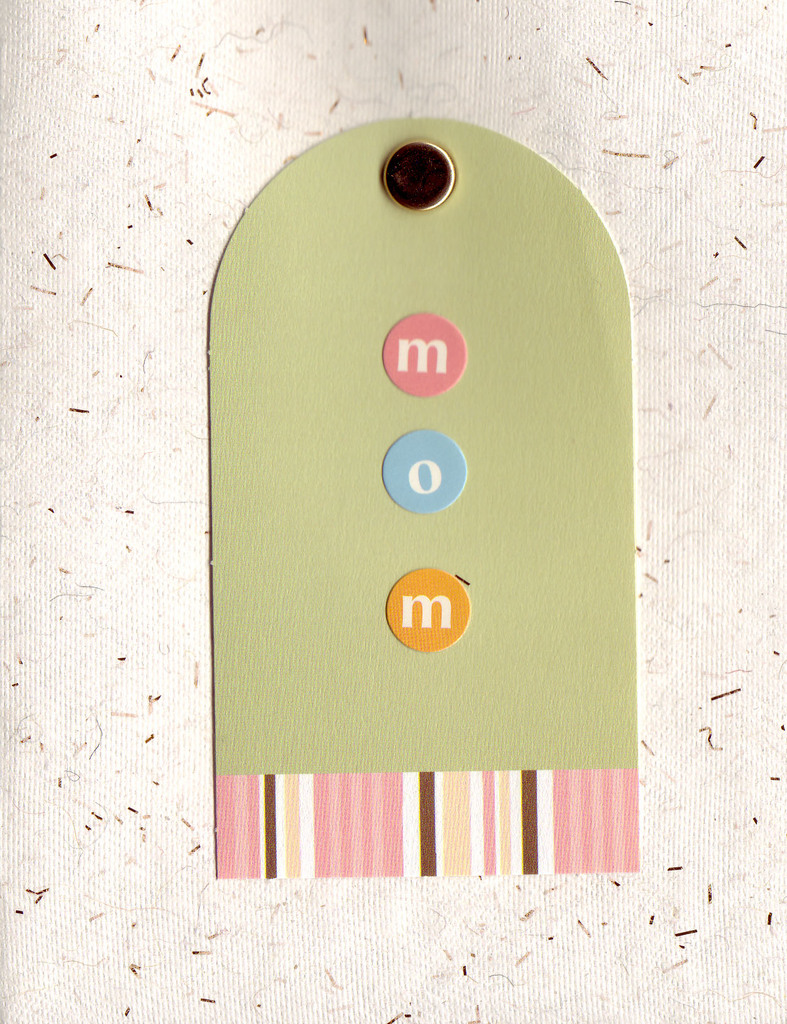 015 - 'Mom' on a tag attached by a brad to an ivory flocked paper